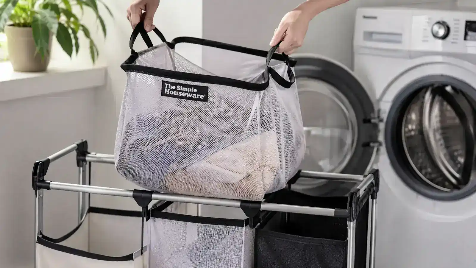 A close-up of the removable laundry bag being lifted off the rolling sorter frame and carried to the washer