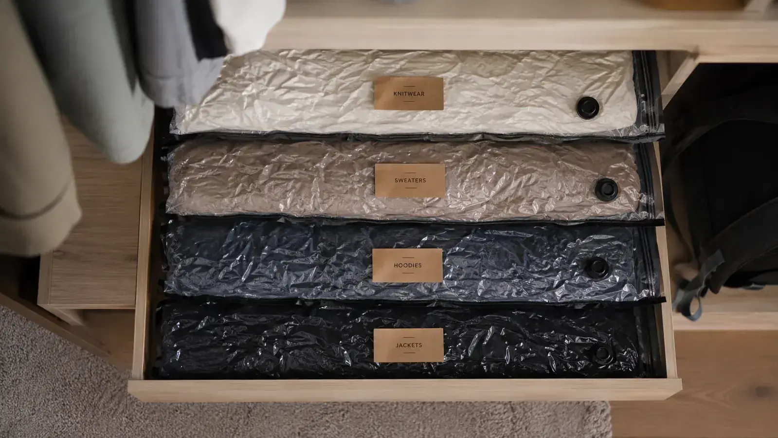 Neatly stacked vacuum-compressed storage bags on a closet shelf next to labeled bins