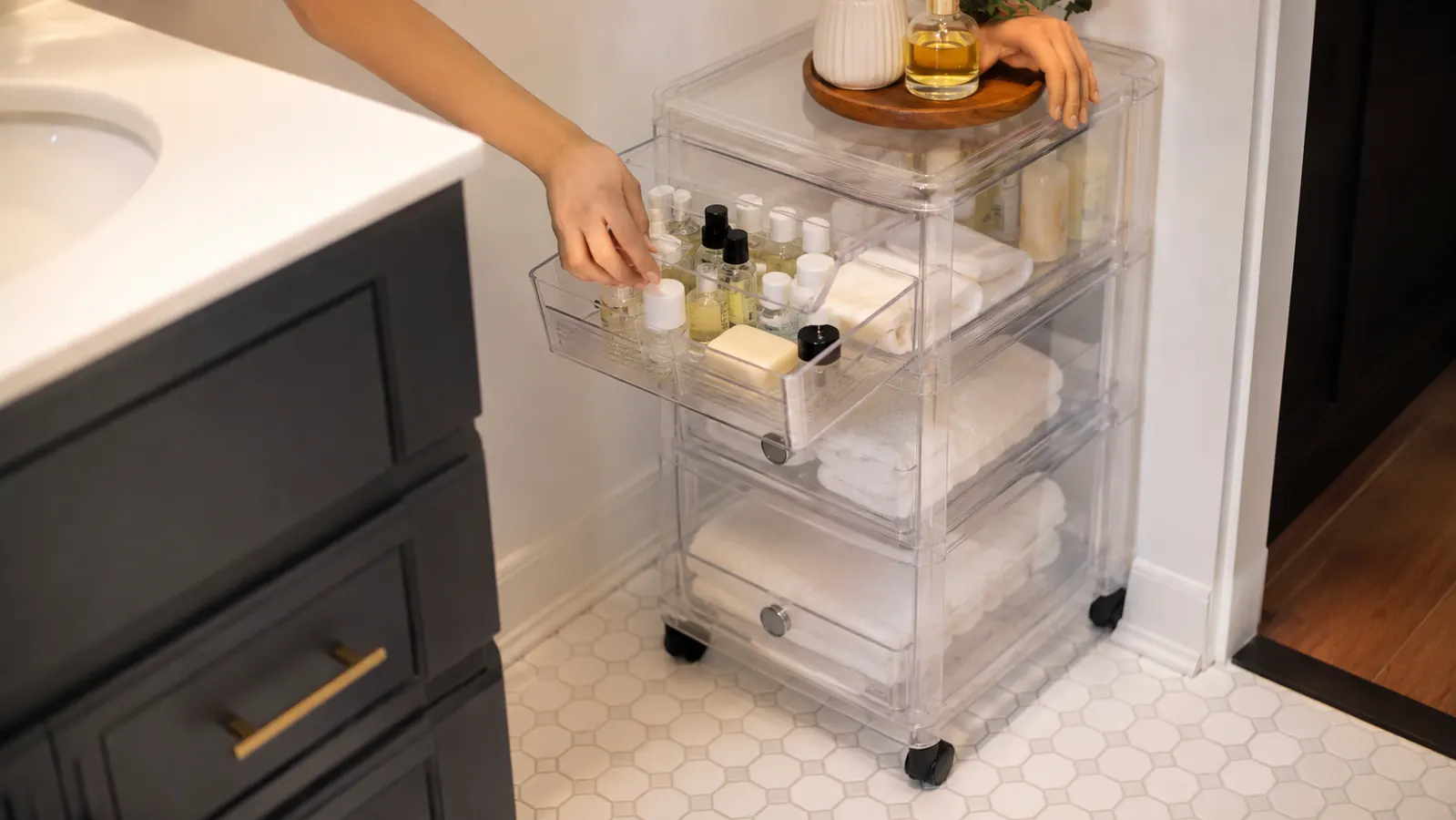 HOMZ rolling drawer cart positioned in a bathroom with its top drawer open revealing organized toiletries and extra soap in clear view through the plastic