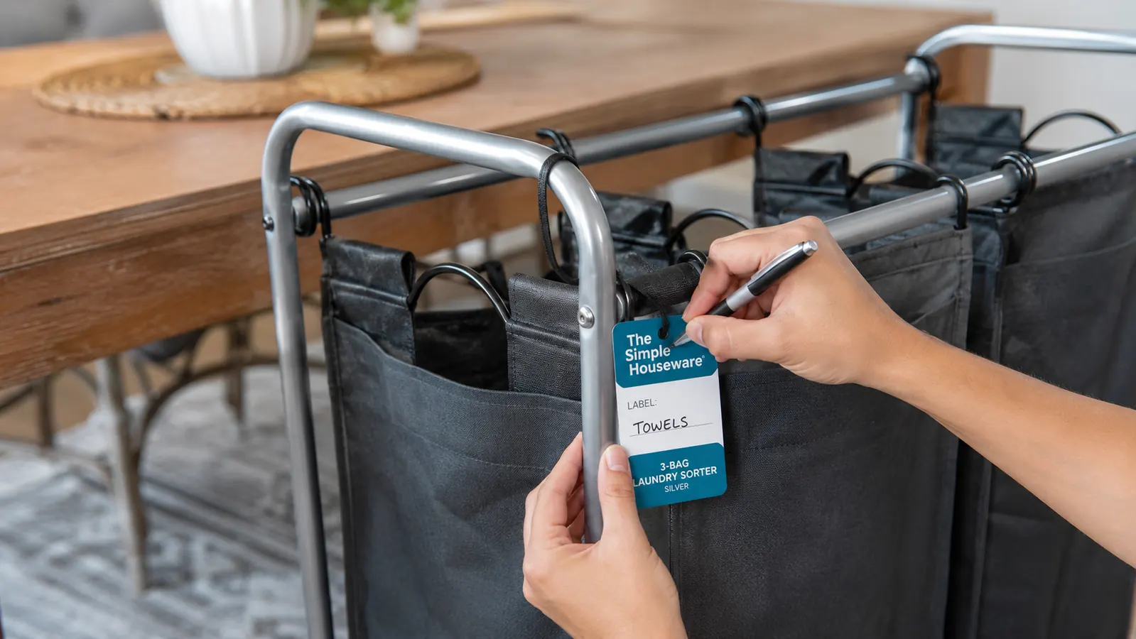 Close-up of a hand attaching a handwritten label to a laundry sorter bag marked Darks