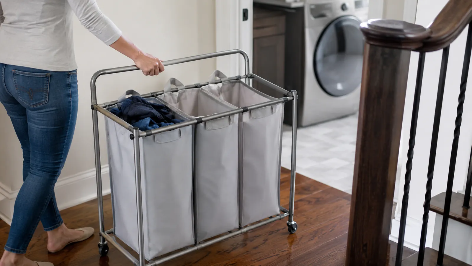 Person rolling a loaded laundry sorter cart from a bedroom hallway toward the laundry room