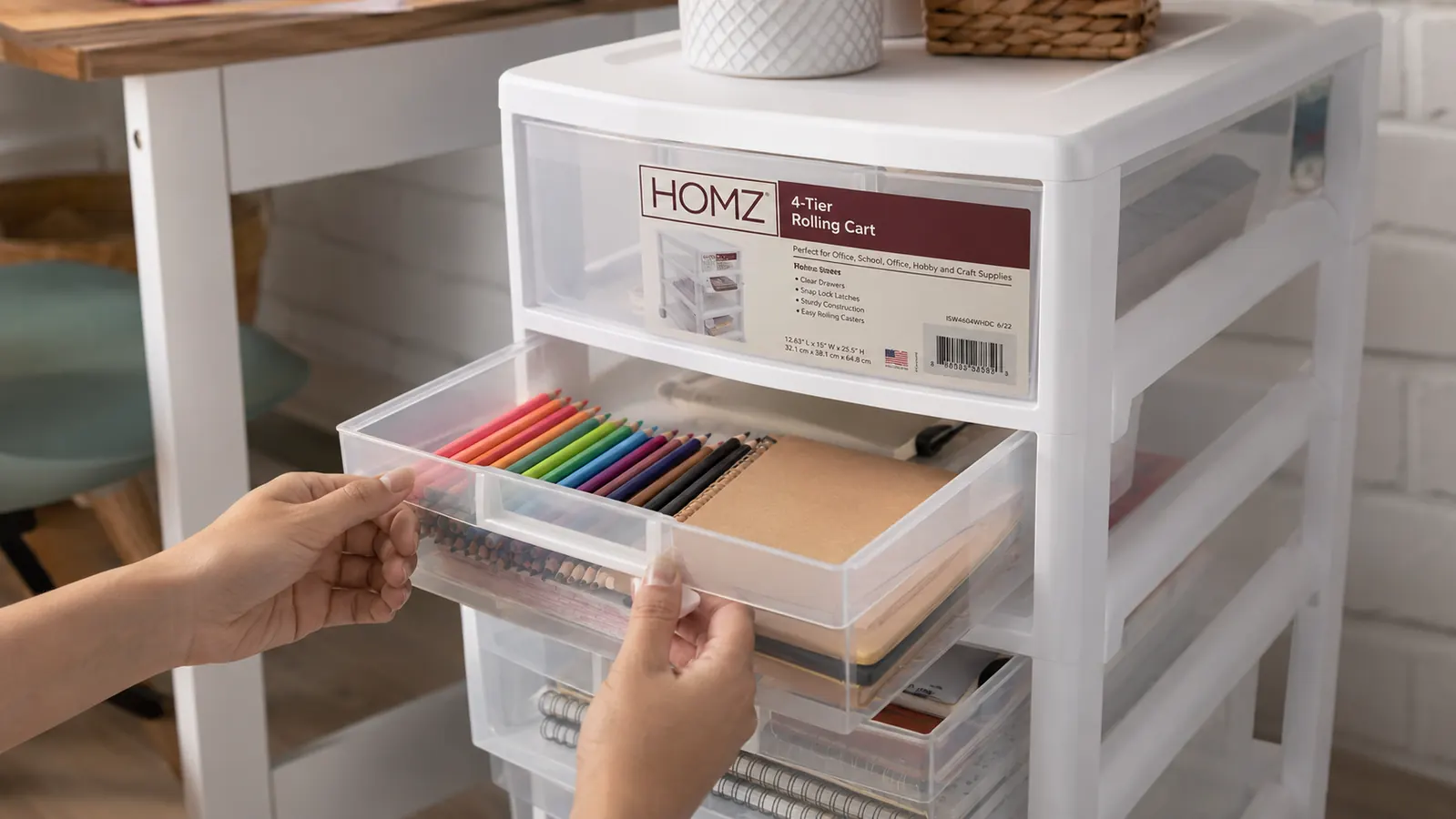 Hands sliding open a clear plastic drawer on a rolling cart filled with sorted craft supplies